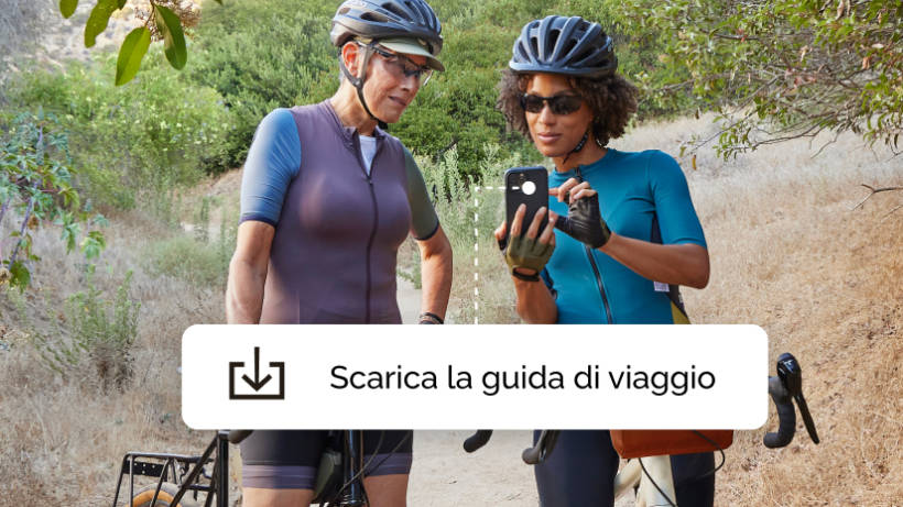 Due donne in un tour in bicicletta, in un momento di pausa per scaricare un’app di guida di viaggio offerta dalla campagna di Mailchimp.