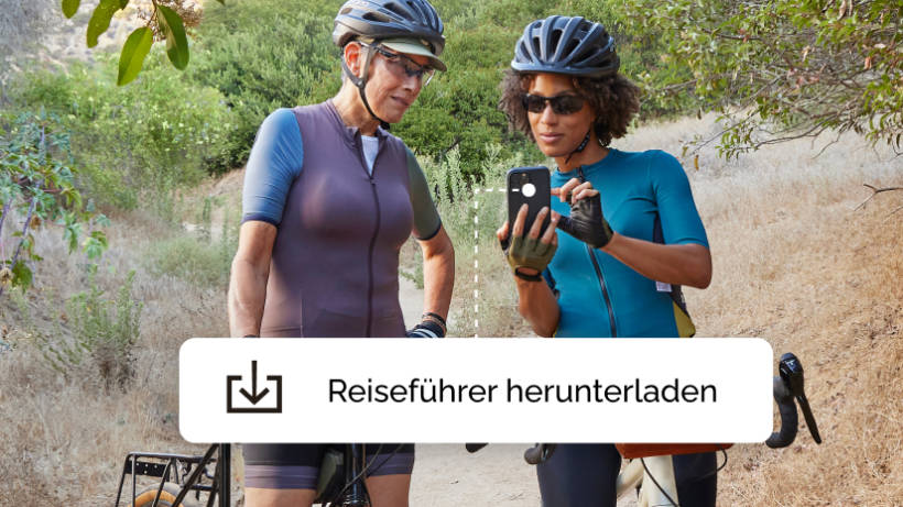 Zwei Frauen bei einer Radtour, die anhalten, um einen Reiseführer herunterzuladen, der von einer Mailchimp-Kampagne angeboten wird.