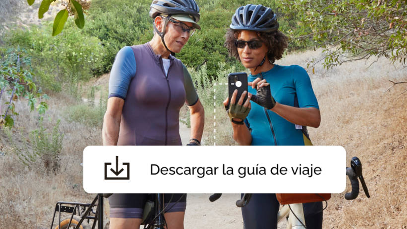 Dos mujeres en un viaje en bicicleta, haciendo una pausa para descargar una aplicación de guías de viaje que ofrece una campaña de Mailchimp.